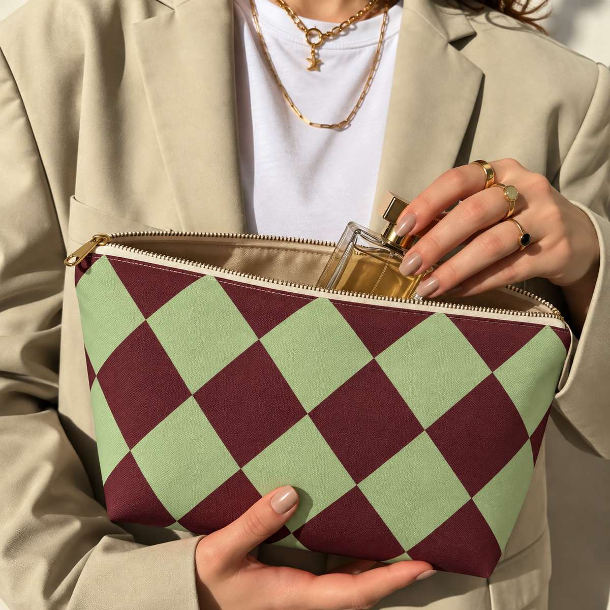 Hands holding the green burgundy checkered makeup bag with a perfume bottle inside