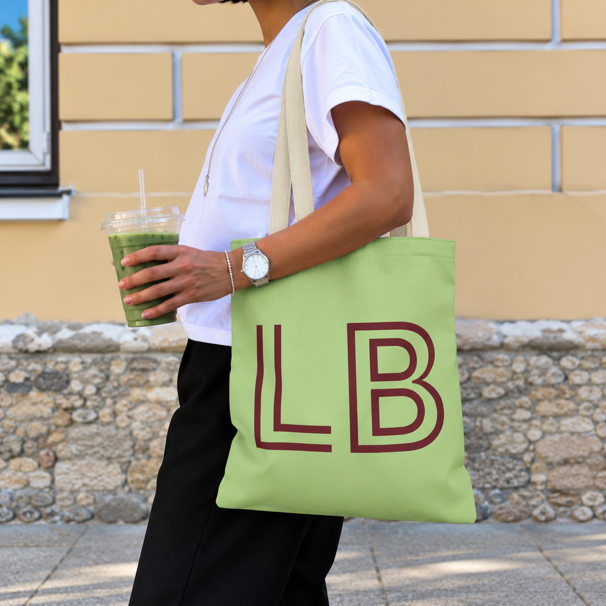Woman with an iced drink wearing the green burgundy monogram personalized tote bag