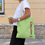 Woman carrying the Green Burgundy Name personalized tote bag, side view with an iced drink
