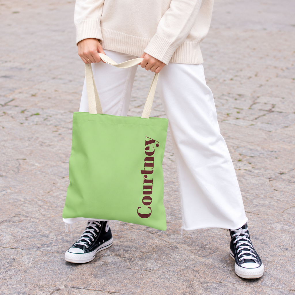 Model holding the Green Burgundy Name personalized tote bag in front of white trousers