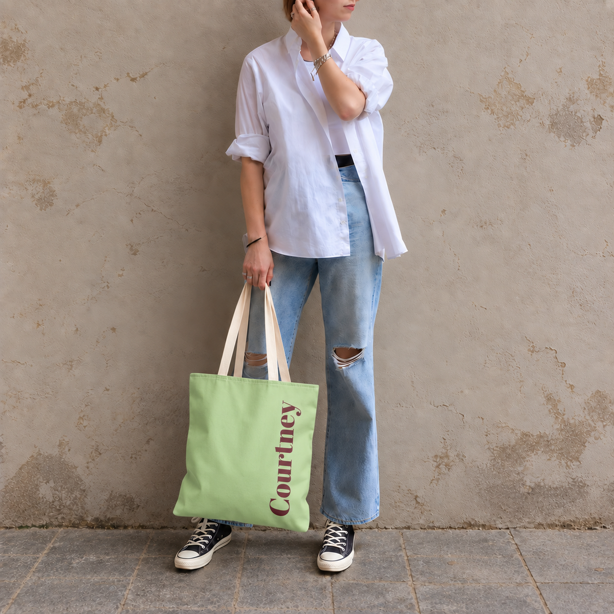 Model standing outdoors with the Green Burgundy Name personalized tote bag in a full-body photo