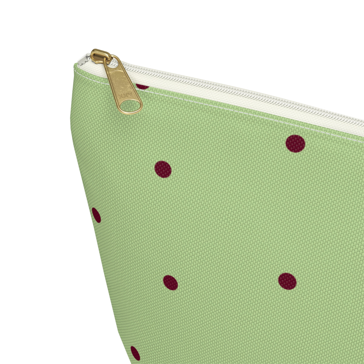 Close-up of the gold zipper pull and burgundy dots on the green makeup bag