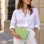 Woman in white shirt holding the green burgundy polka dot makeup bag as a clutch