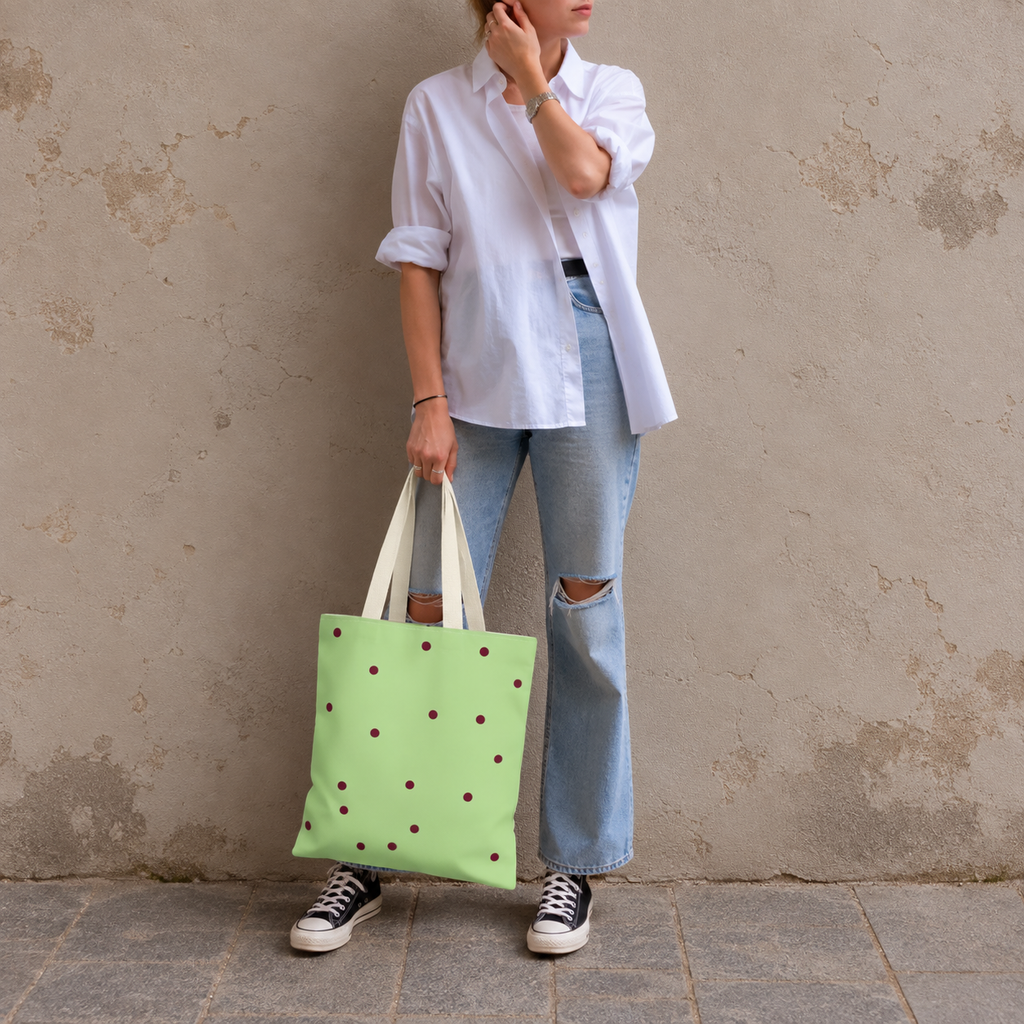 Woman in jeans and sneakers holding the green burgundy polka dot tote bag