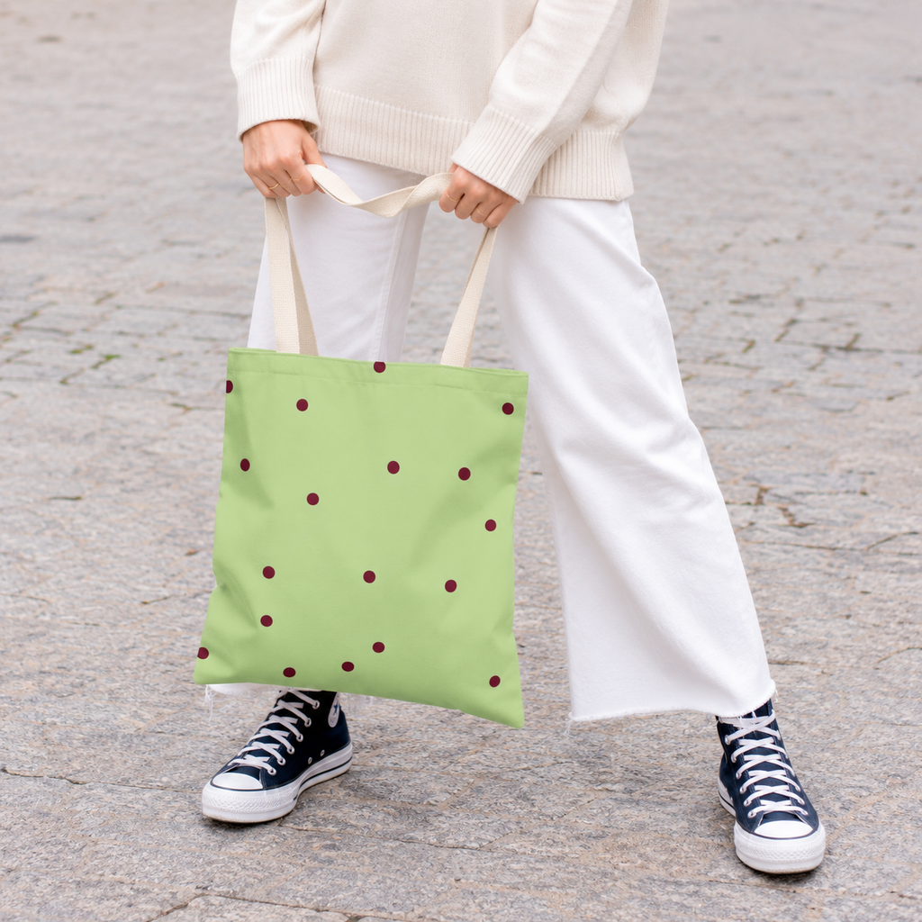 Woman in white trousers carrying the green burgundy polka dot tote bag