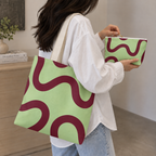 Woman carrying the matching tote bag and holding the green burgundy wavy line makeup bag