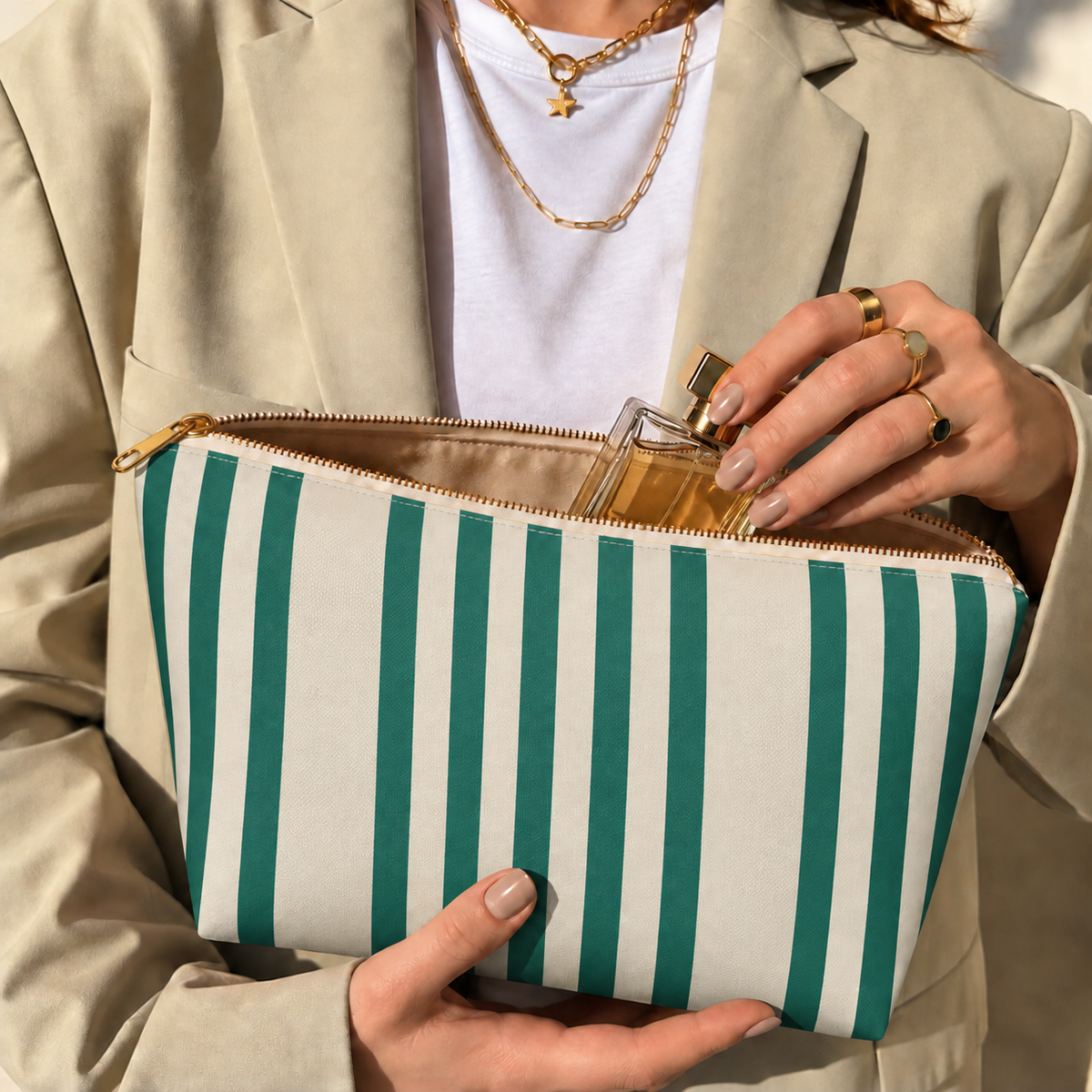 Hands holding the open Green Cream Striped makeup bag filled with cosmetics