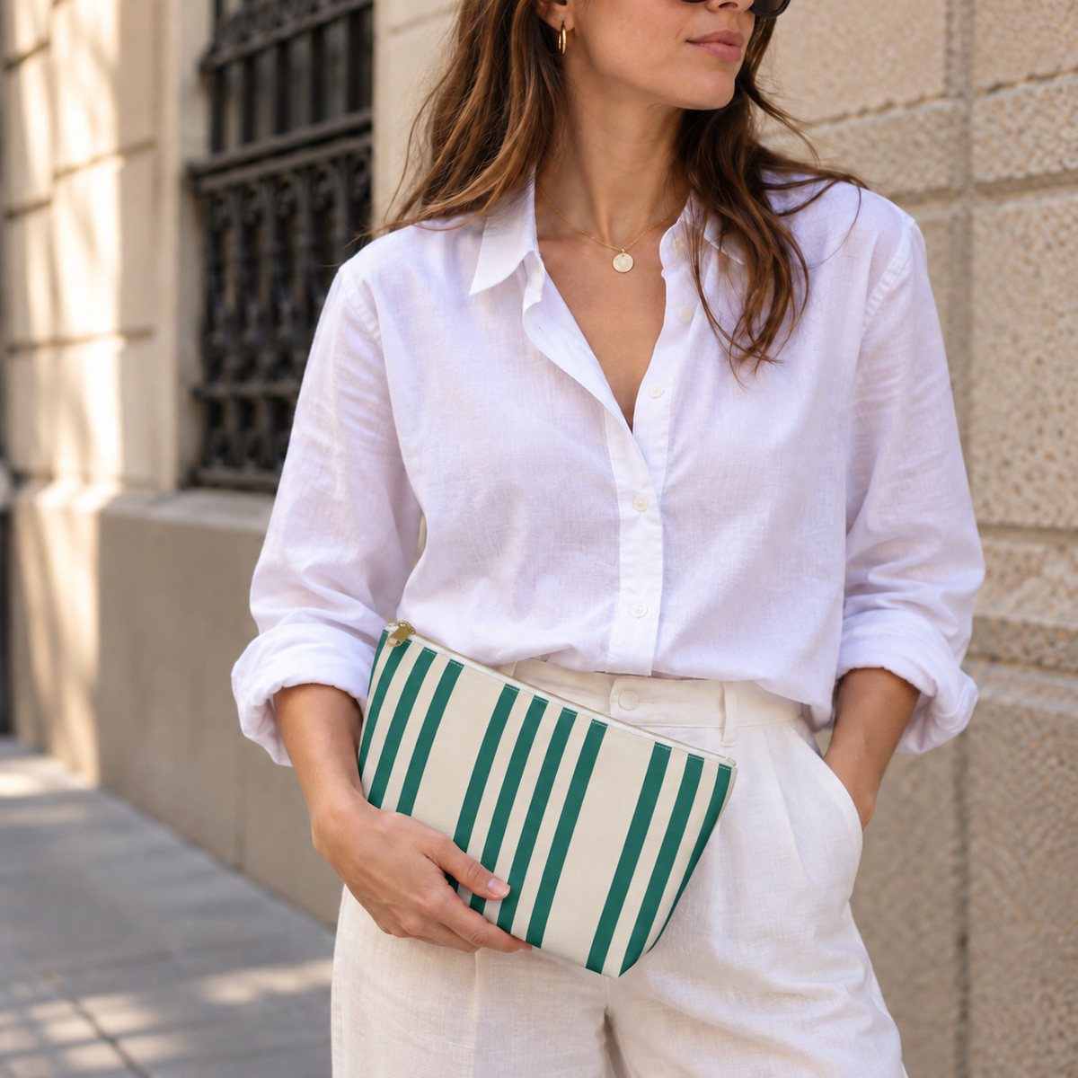 Model holding the Green Cream Striped makeup bag like a clutch