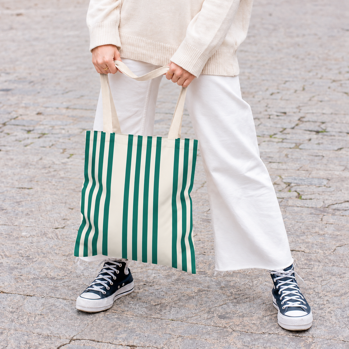Model in white trousers carrying the Green Cream Striped tote bag