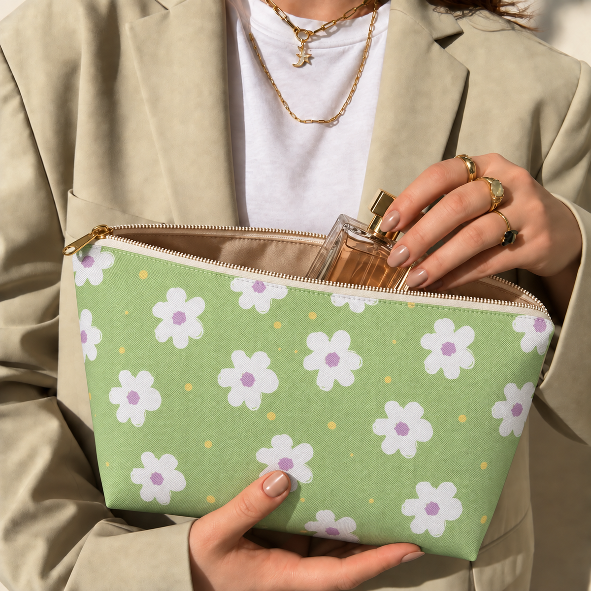 Model opening the green daisy floral makeup bag to take out a perfume bottle