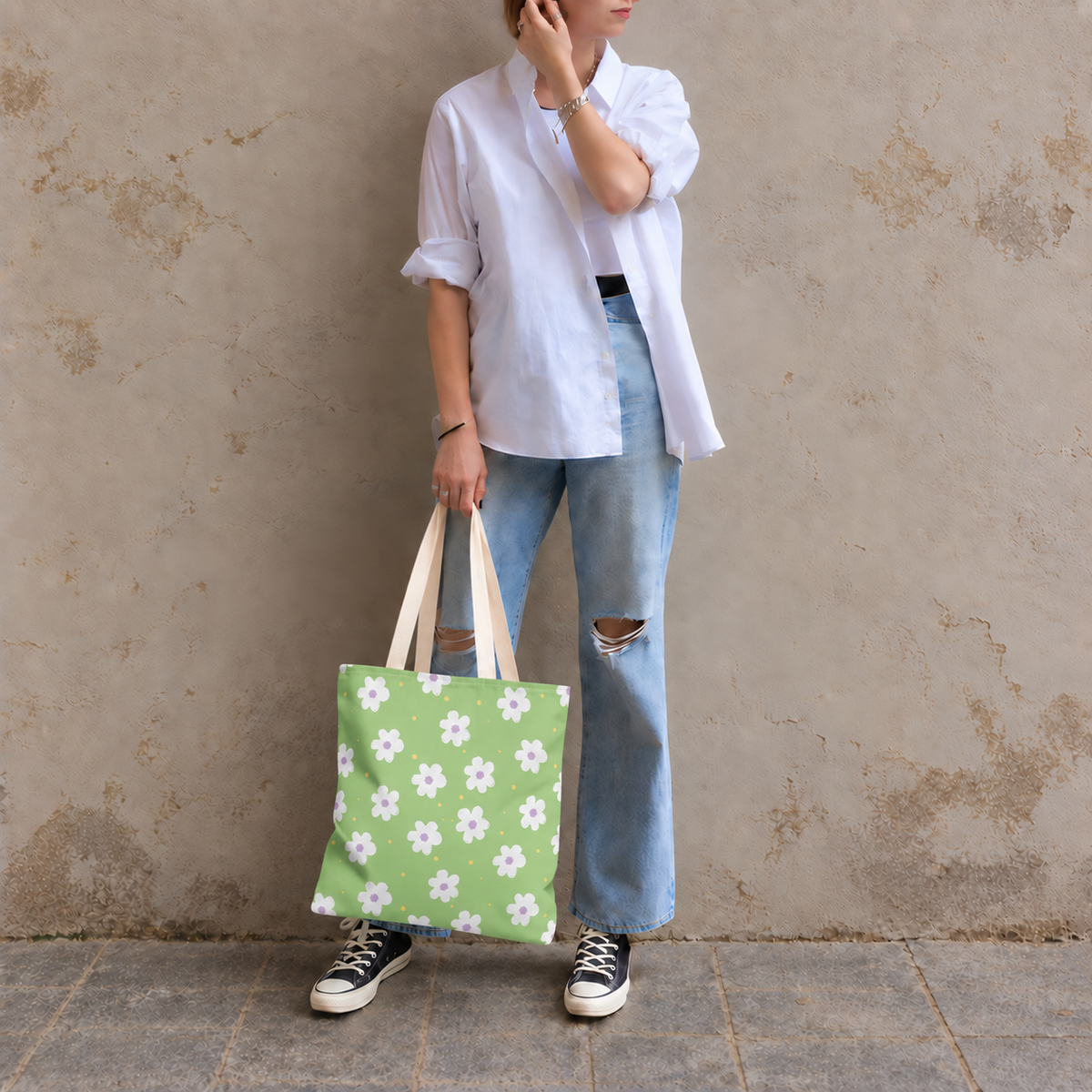 Model in jeans standing with the green daisy tote bag in her hand