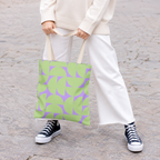 Model holding the green lavender half circle tote bag in front of white trousers