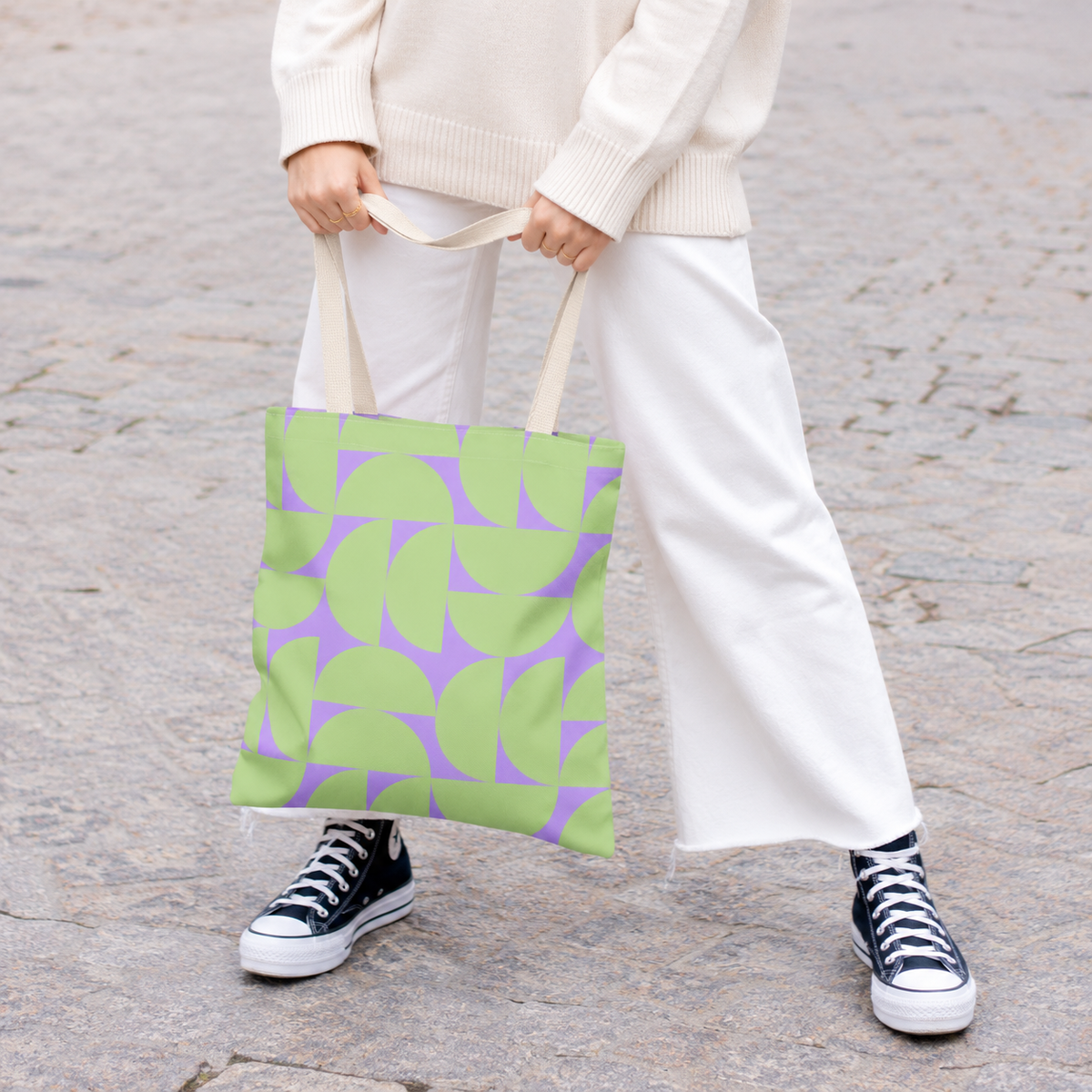 Model holding the green lavender half circle tote bag in front of white trousers