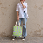 Model in jeans and a white shirt standing with the green lavender half circle tote bag