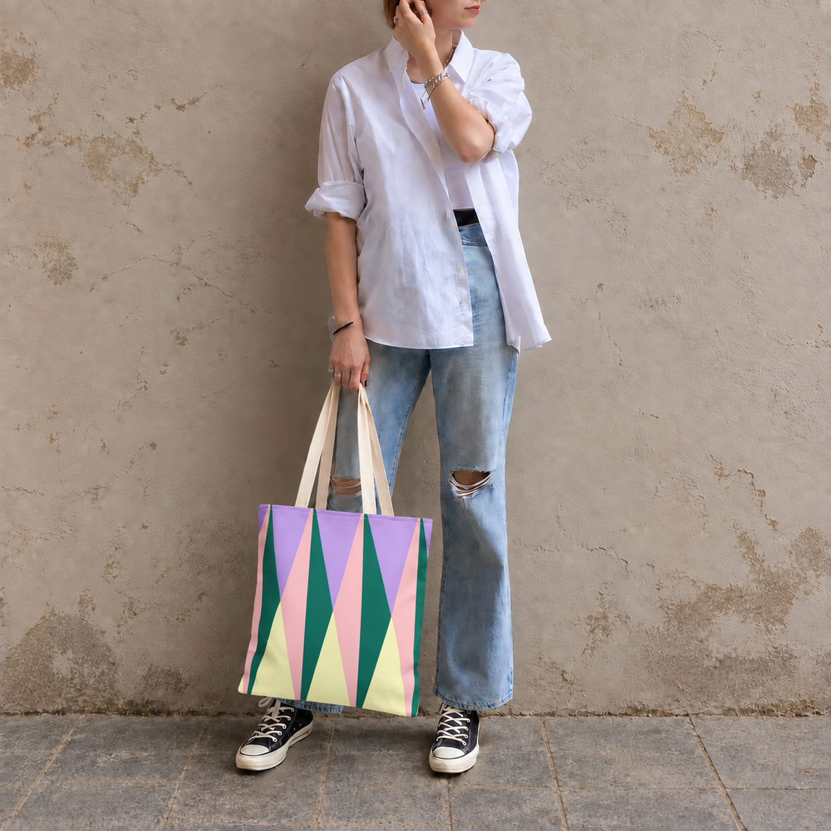 Model in jeans standing with the triangle tote bag in green and pink