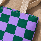 Close-up of the green purple checkered print and handle on the tote bag