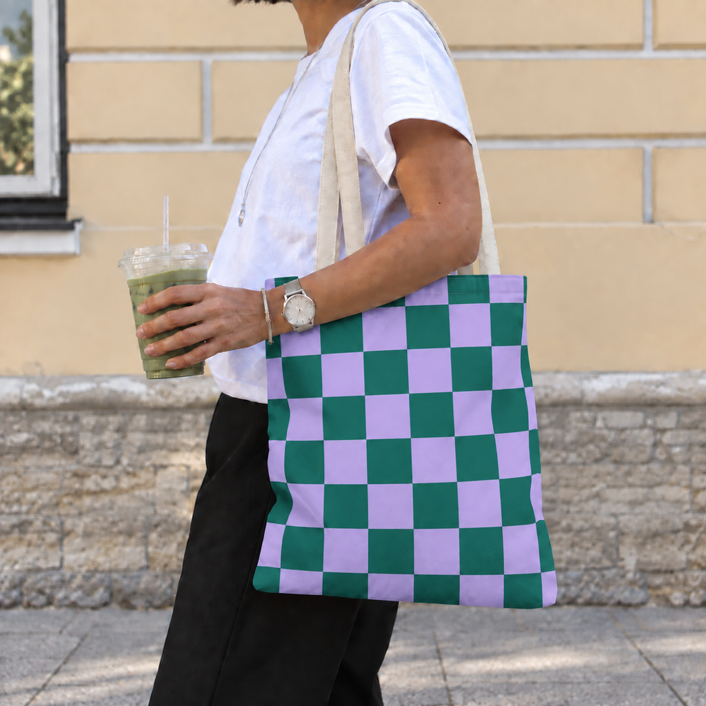 Woman carrying the green purple checkered tote bag on her shoulder while holding a drink