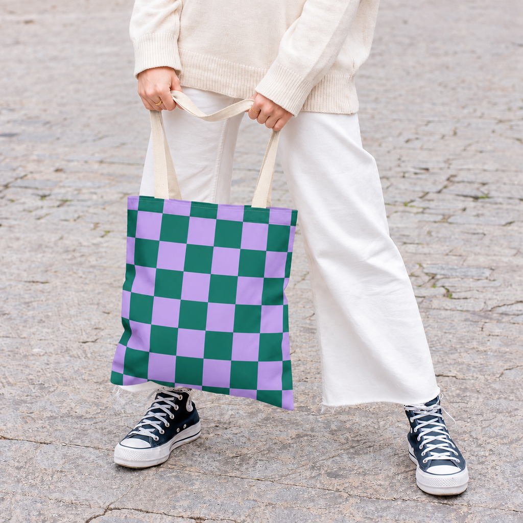 Woman in white trousers holding the green purple checkered tote bag by the handles