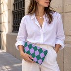 Woman in white shirt holding the green purple checkered makeup bag as a clutch