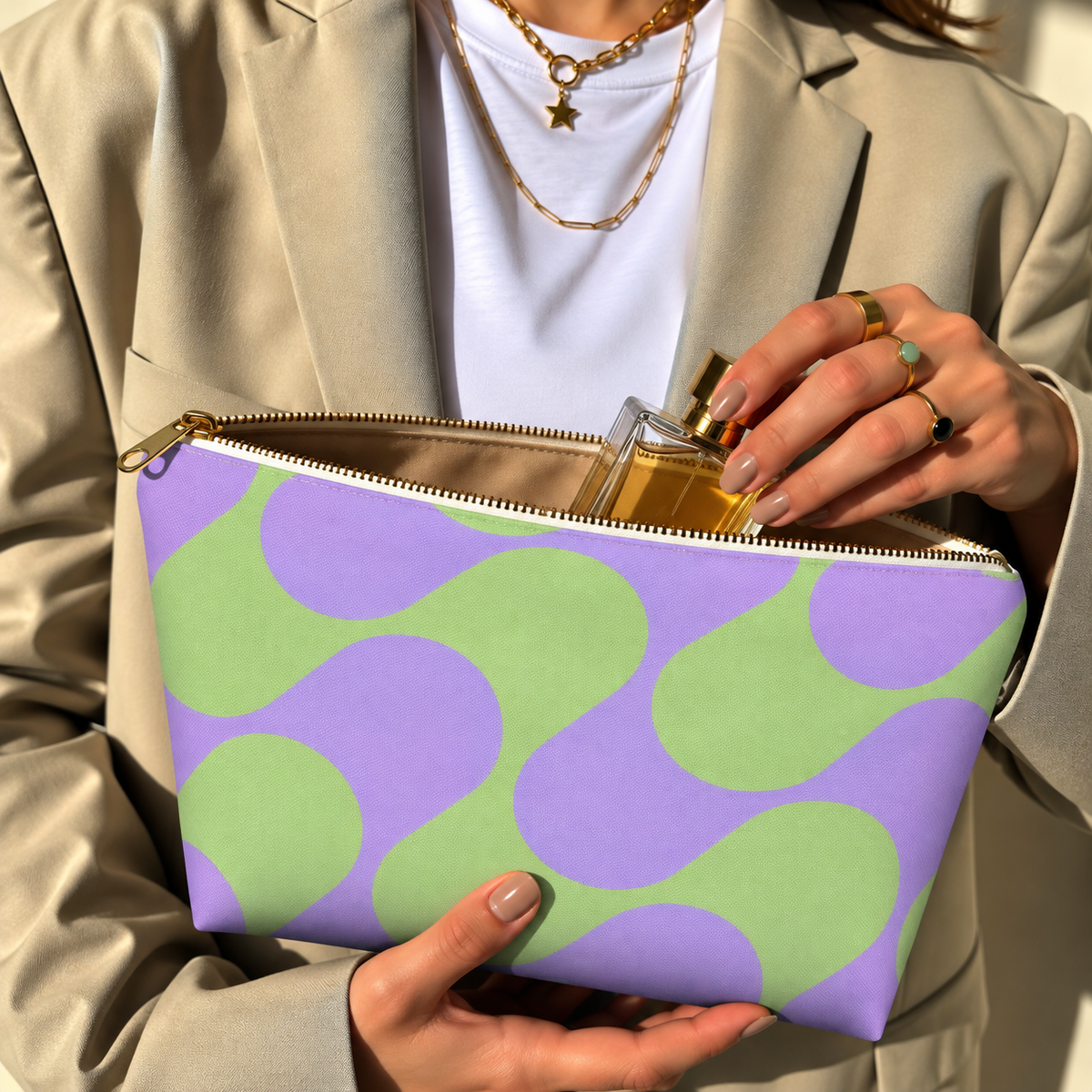 Woman holding the green purple geometric makeup bag open with the gold zipper