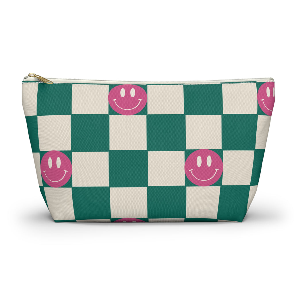 Green and cream checkered makeup bag with pink smiley faces and gold zipper pull on a white background