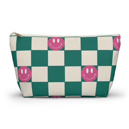 Green and cream checkered makeup bag with pink smiley faces and gold zipper pull on a white background