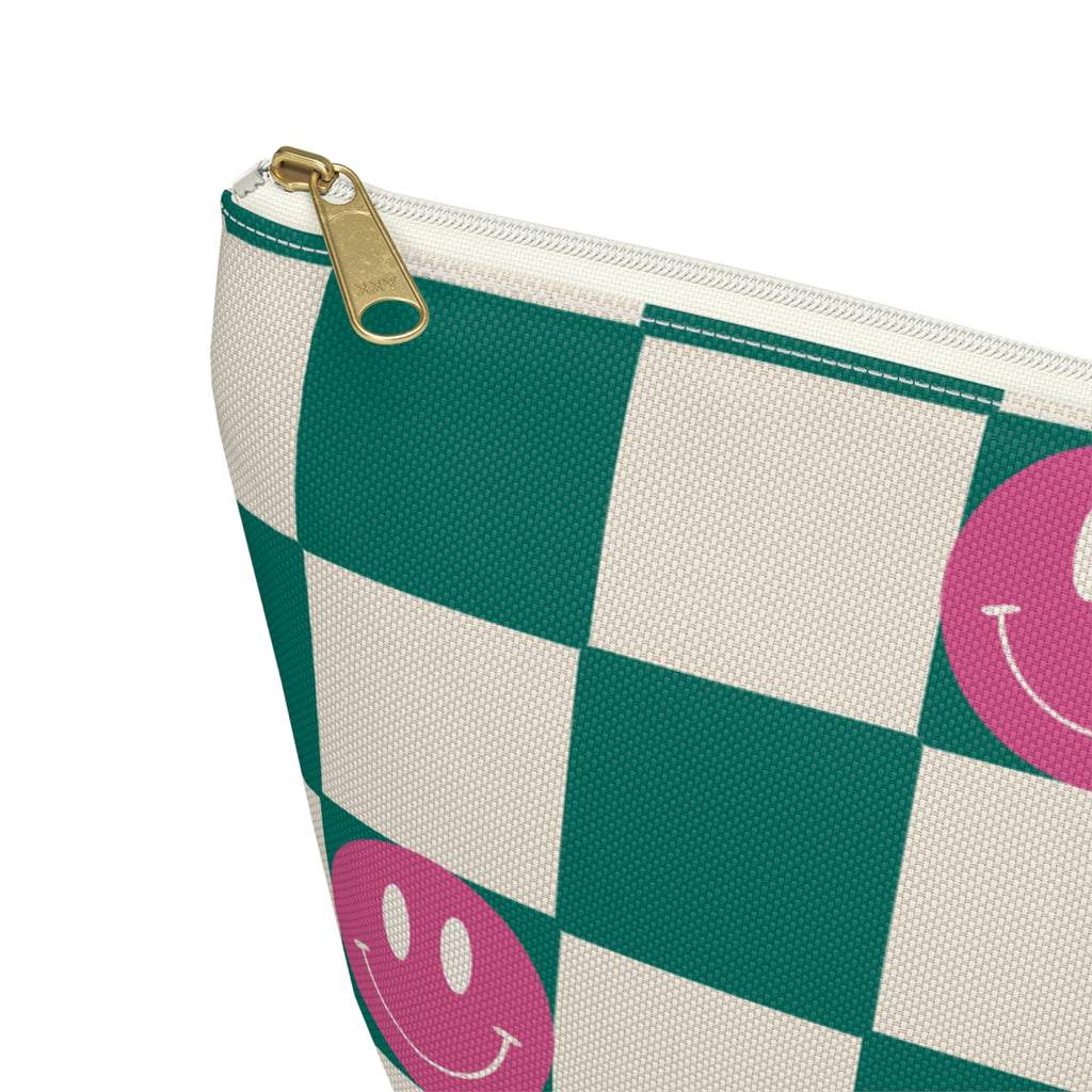 Close-up of the gold zipper pull and pink smiley face on the checkered makeup bag
