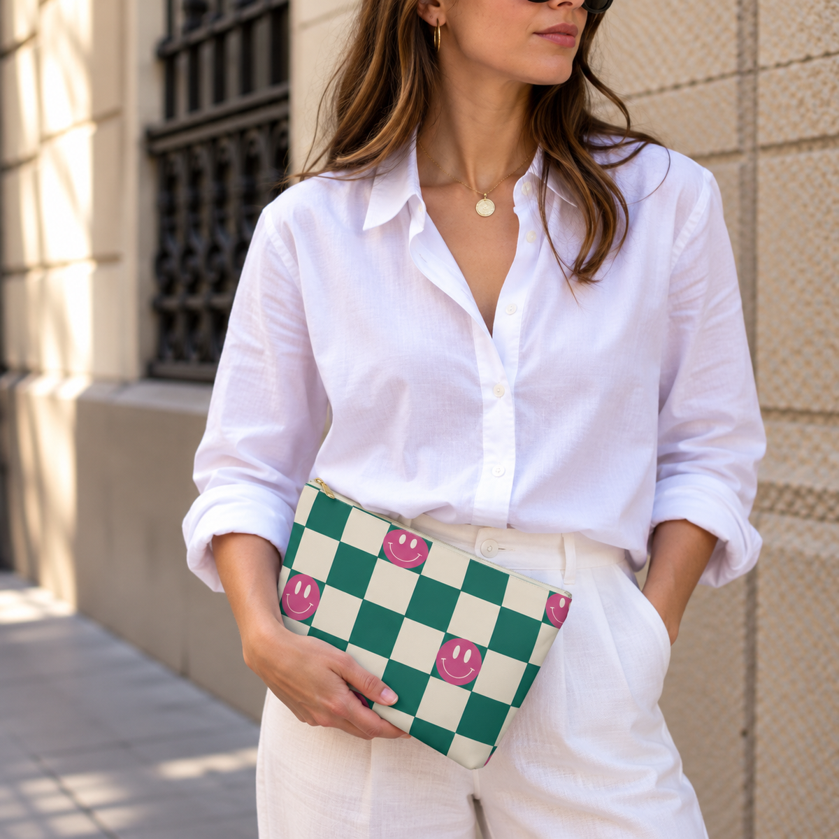 Model holding the green smiley checkered makeup bag like a clutch