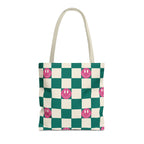 Green and cream checkered tote bag with pink smiley faces and cream handles on a white background
