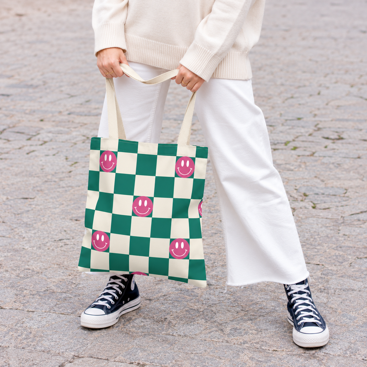 Model holding the green smiley checkered tote bag by its handles