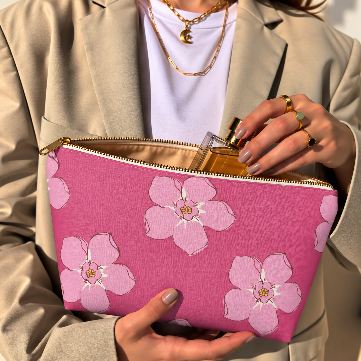Model opening the hot pink floral makeup bag to take out a perfume bottle