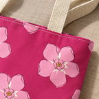 Close-up of a light pink blossom on hot pink fabric next to the tote handle