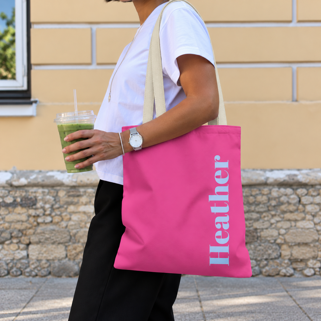 Woman carrying the Hot Pink Blue Name personalized tote bag, side view with an iced drink