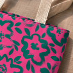 Close-up of the green flower print on hot pink and the cream handle of the tote bag