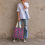 Woman in a white shirt and jeans standing with the hot pink green floral tote bag