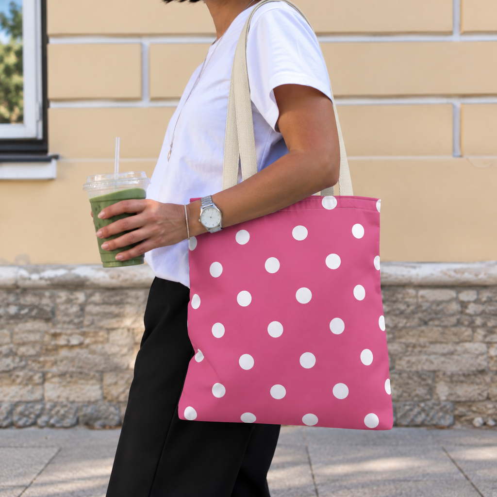 Woman walking with the hot pink polka dot tote bag on her shoulder and an iced drink