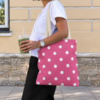 Woman walking with the hot pink polka dot tote bag on her shoulder and an iced drink