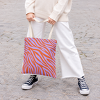 Woman in white trousers and sneakers holding the lavender orange zebra print tote bag