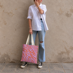Woman in a white shirt and jeans holding the lavender orange zebra print tote bag