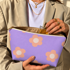 Hands holding the open daisy makeup bag with a perfume bottle inside