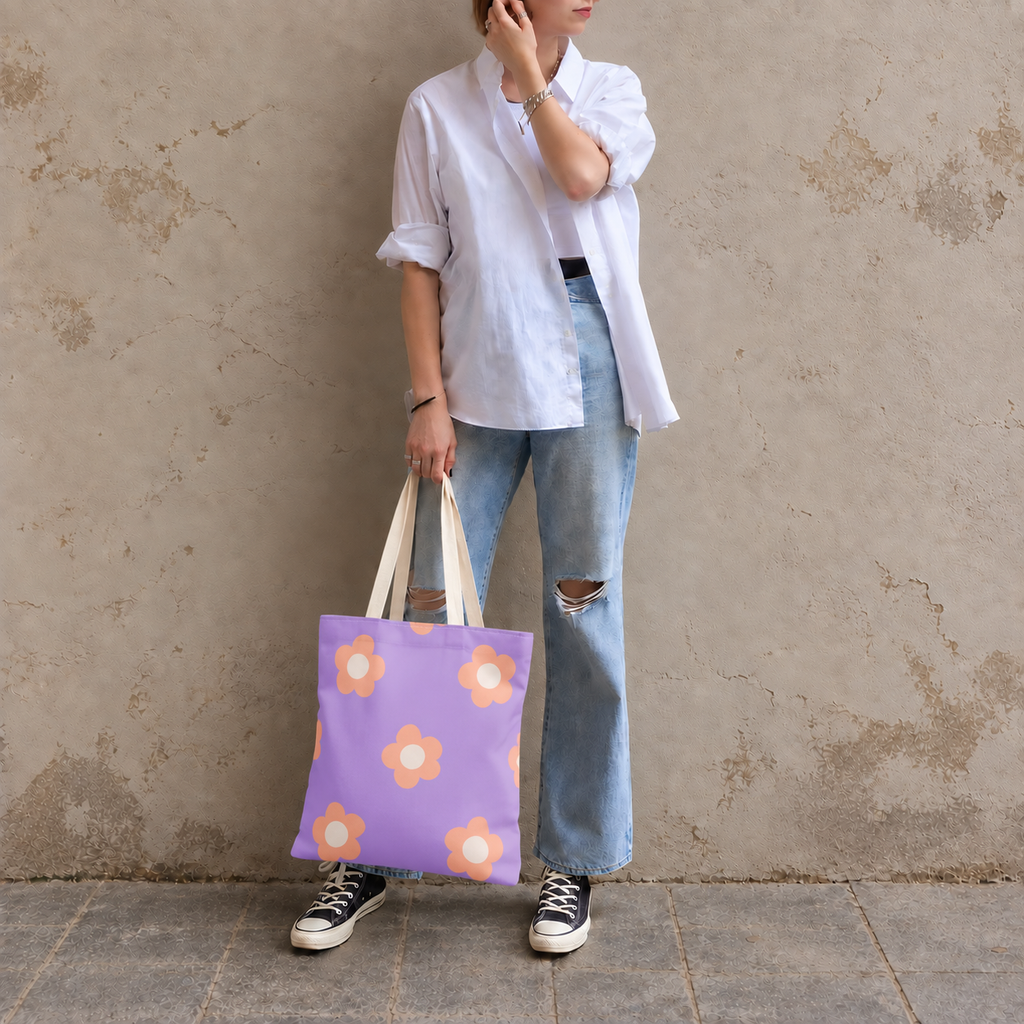 Woman in a white shirt and jeans standing with the lavender peach daisy tote bag