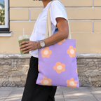 Woman with an iced drink wearing the lavender peach daisy tote bag on her shoulder