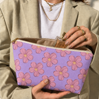 Model opening the lavender floral makeup bag to take out a perfume bottle