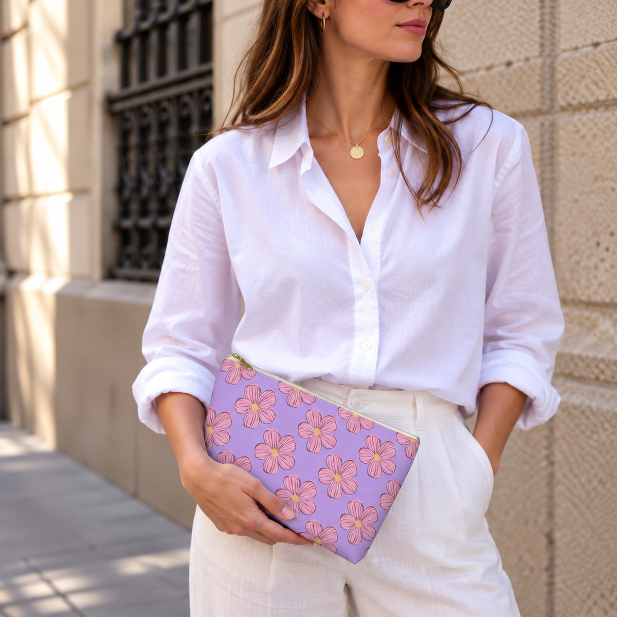 Model in a white shirt holding the lavender pink floral makeup bag at her waist