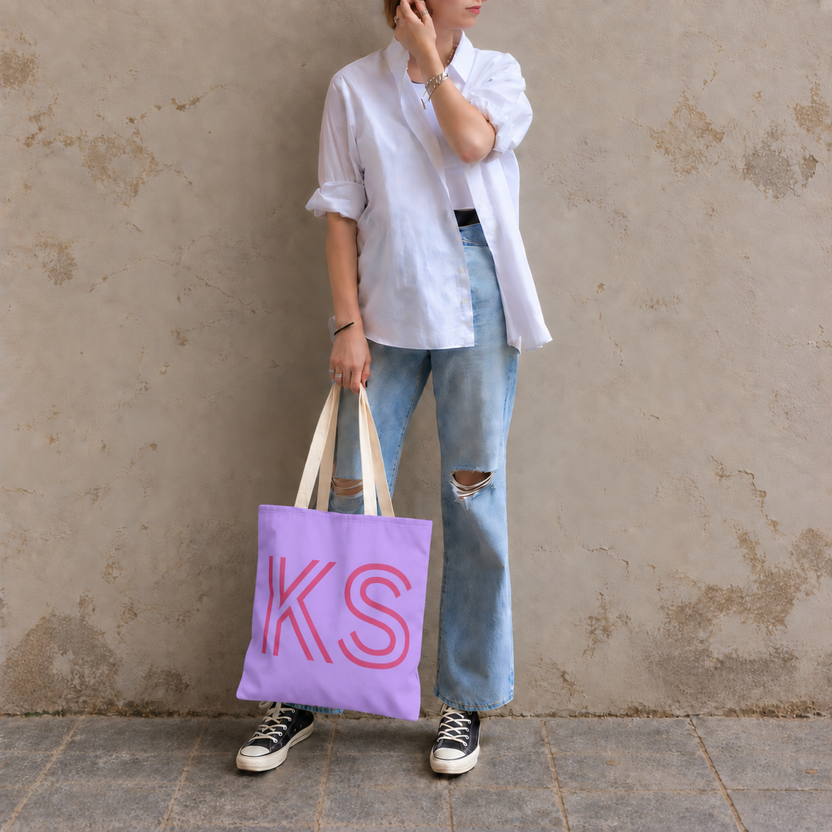 Woman in a white shirt and jeans standing with the lavender personalized tote bag