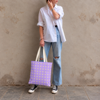 Woman in a white shirt and jeans holding the lavender polka dot tote bag