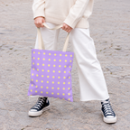 Woman in white trousers and sneakers holding the lavender yellow polka dot tote bag