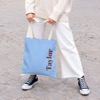 Model holding the Light Blue Burgundy Name personalized tote bag in front of white trousers