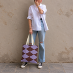 Model in jeans and a white shirt standing with the lilac burgundy diamond tote bag