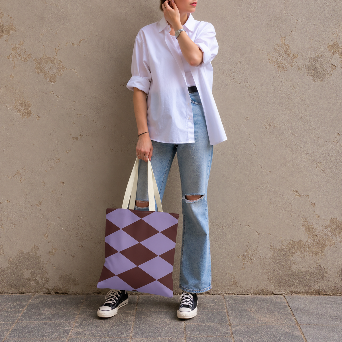 Model in jeans and a white shirt standing with the lilac burgundy diamond tote bag